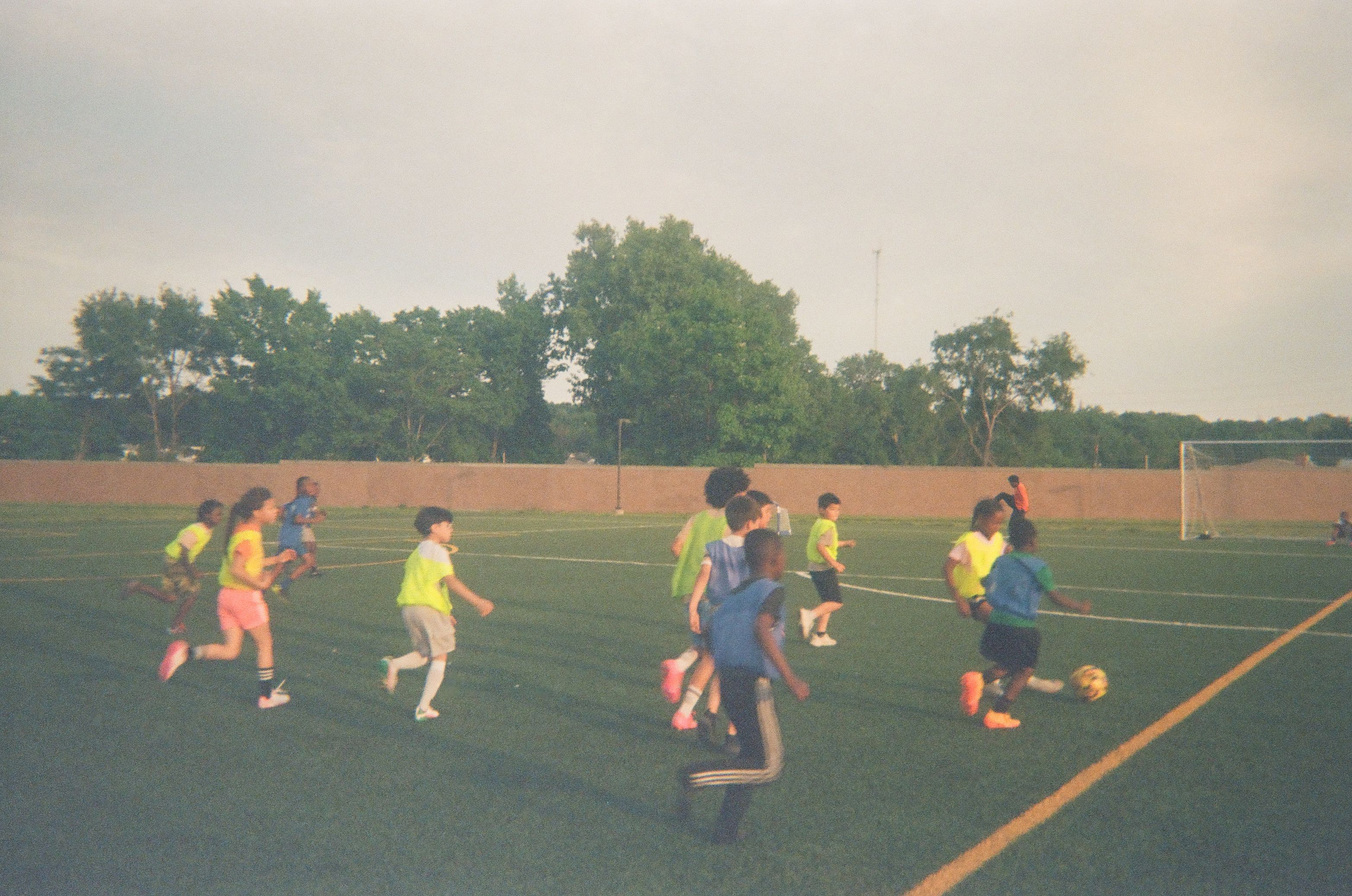 Children play soccer on an outdoor field during a community youth session.