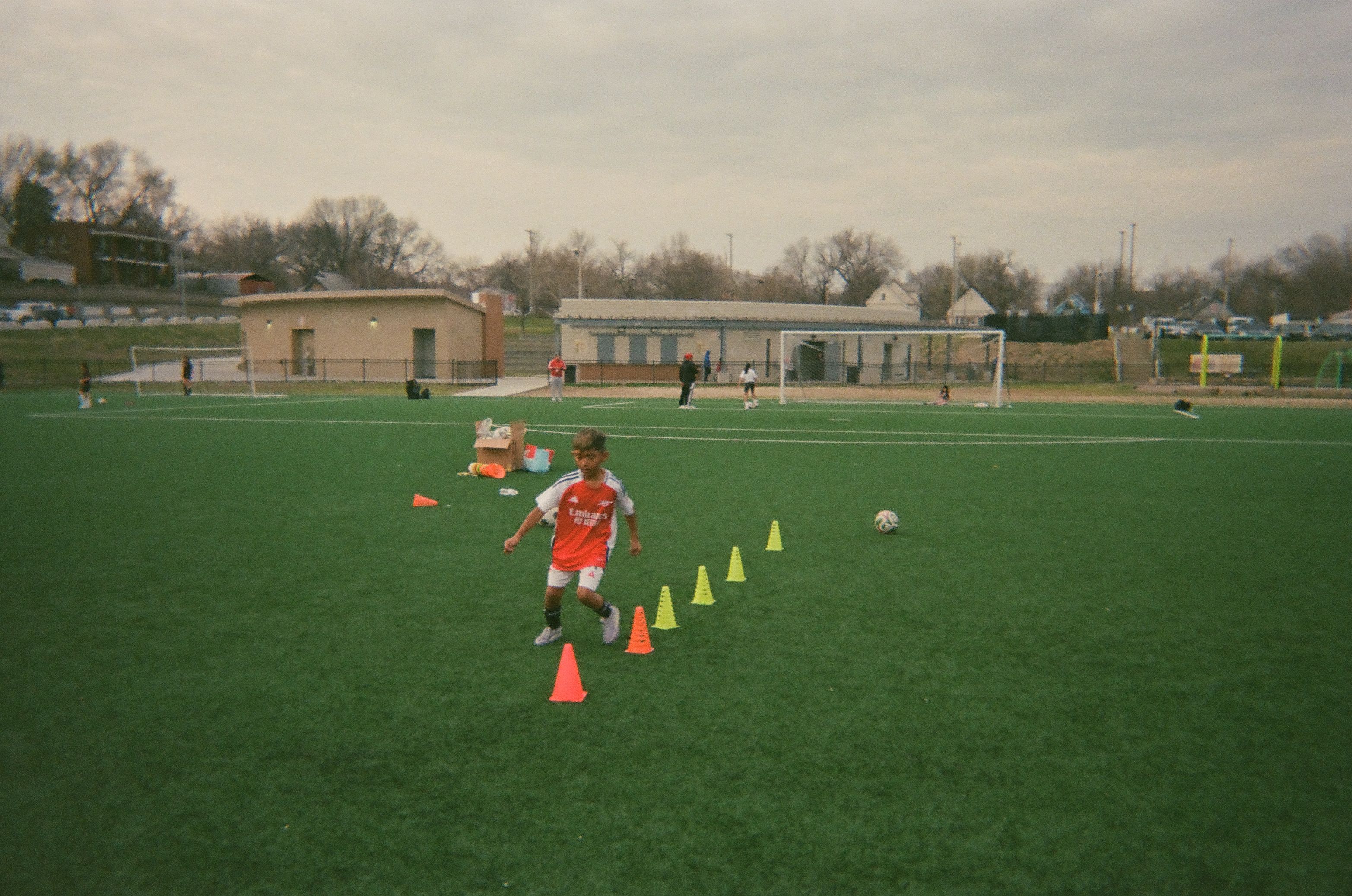 A cild takes part in a soccer training session on an outdoor field.