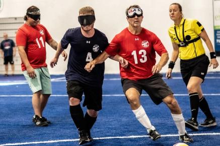 Two blind soccer players battle for a ball on a court
