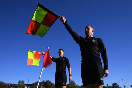 Two referees raise flags on the sidelines
