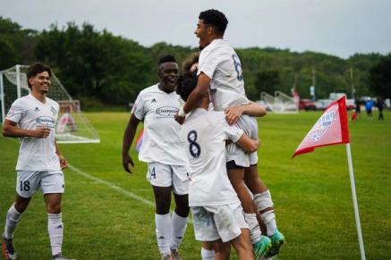 A group of teenager soccer players celebrate on a field