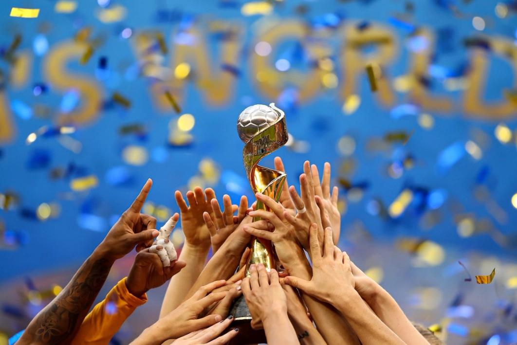 Photo of hands holding World Cup trophy as confetti falls