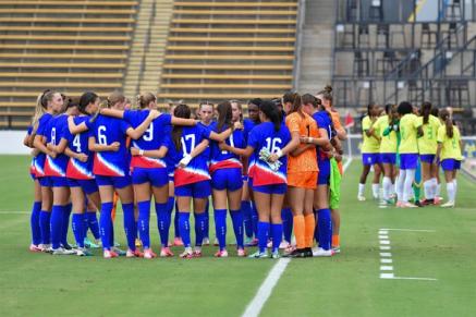 Youth WNT players huddle up on a field