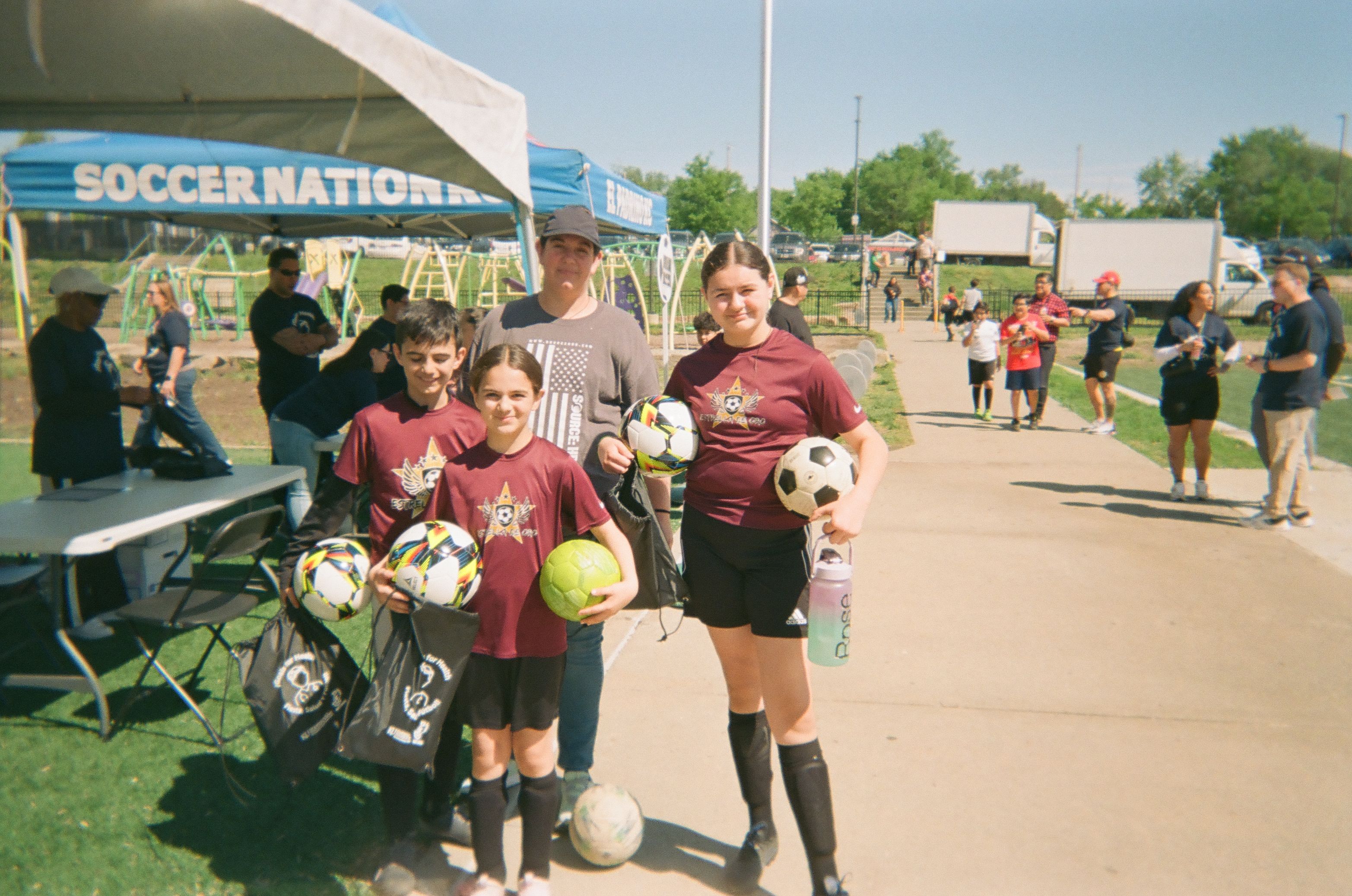 Group of players and a coach standing together holding soccer equipment.