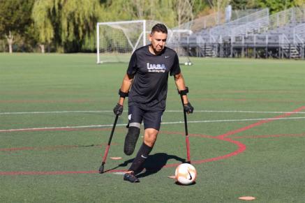 A man on crutches gets ready to kick a soccer ball