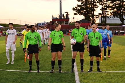Four referees stand at midfield before a match