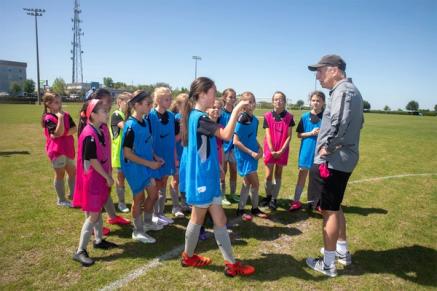 A group of young soccer players on the field with a coach