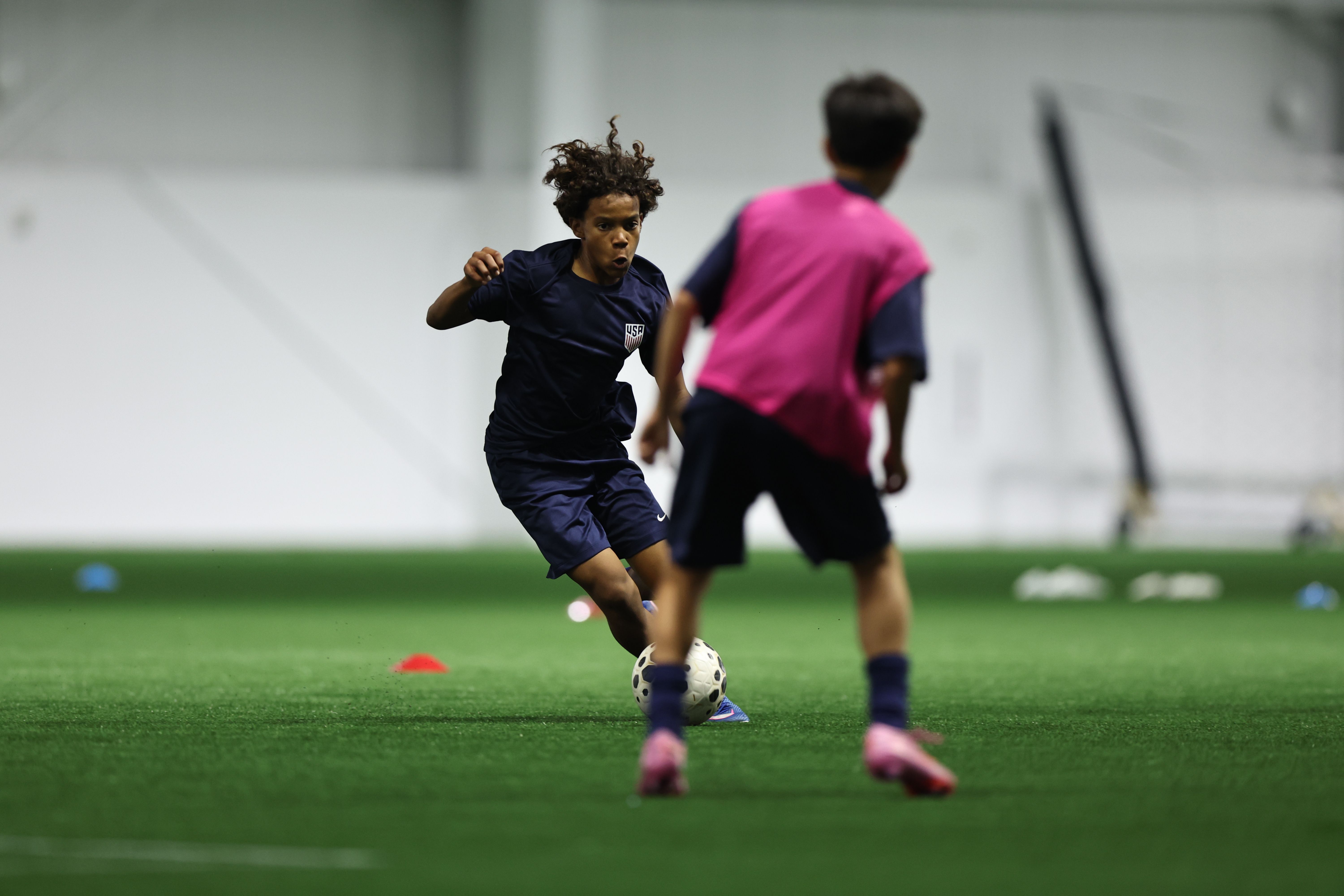 U.S. Soccer coaches observe youth players during an indoor training session.