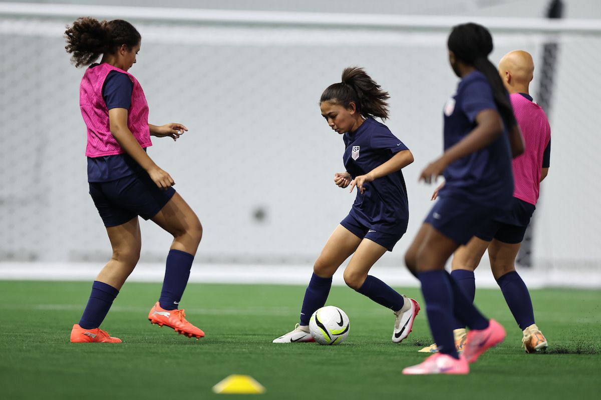 USWNT player dribbling through defenders during a training drill.