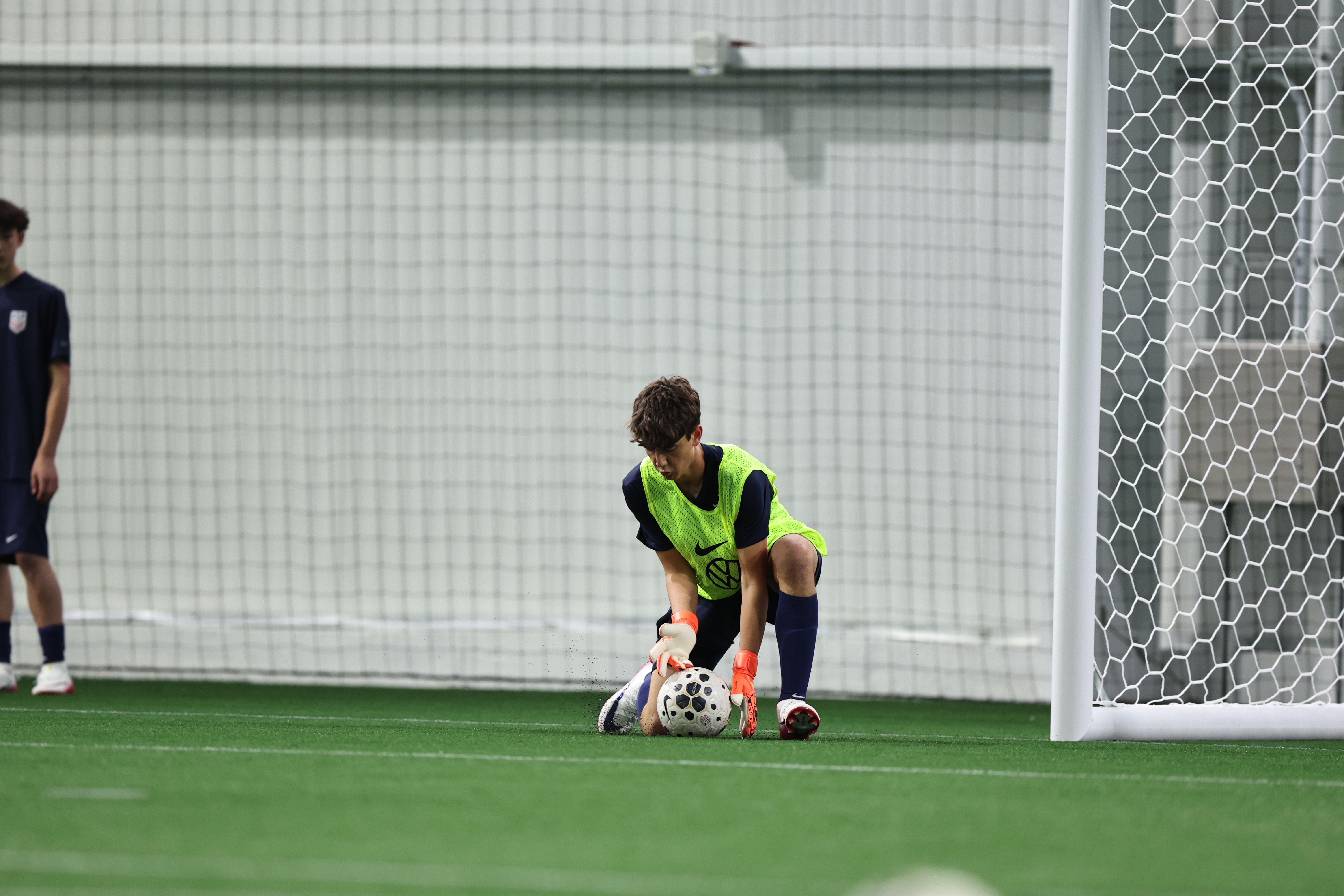 U.S. Soccer player striking a ball during an indoor training session.