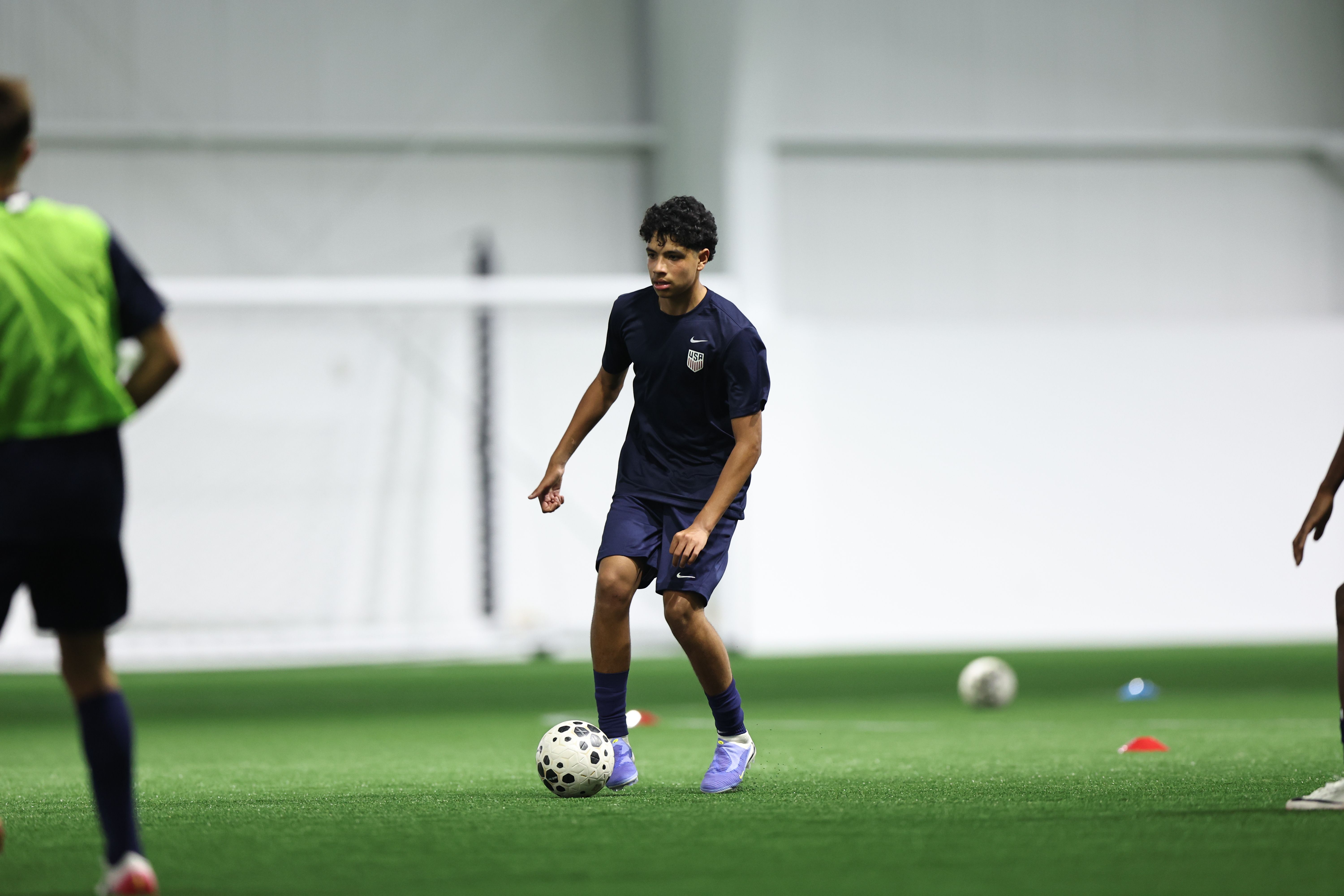 U.S. Soccer player driving through a ball during training.