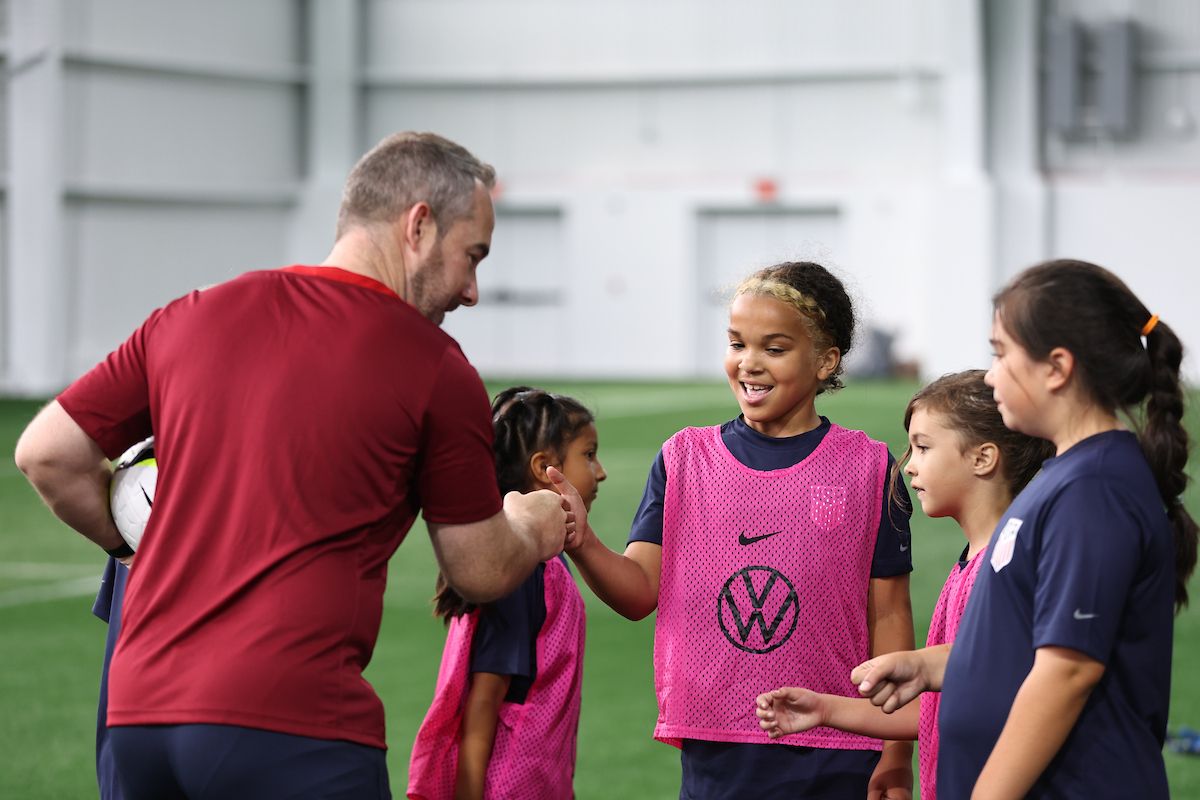 Coach fist-bumping a young girl during a youth soccer session