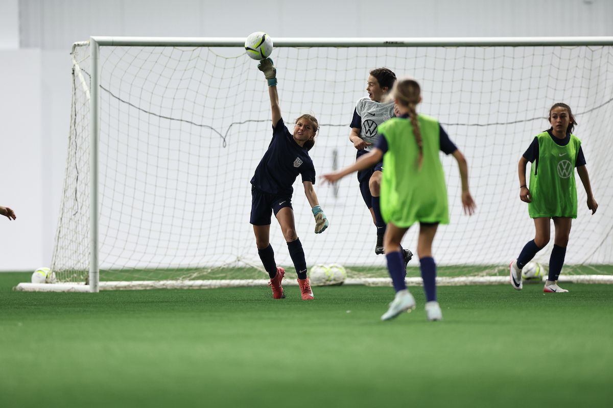 Young player dribbles past a defender during an indoor training drill.