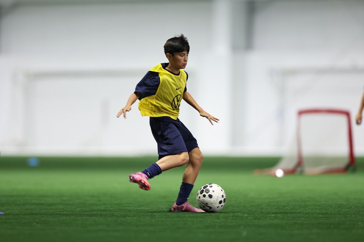 Youth soccer player dribbling indoors during a U.S. Soccer training activity