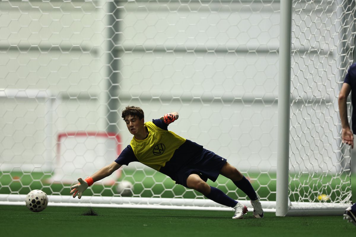 Young girl dribbling a soccer ball during a training drill with other players