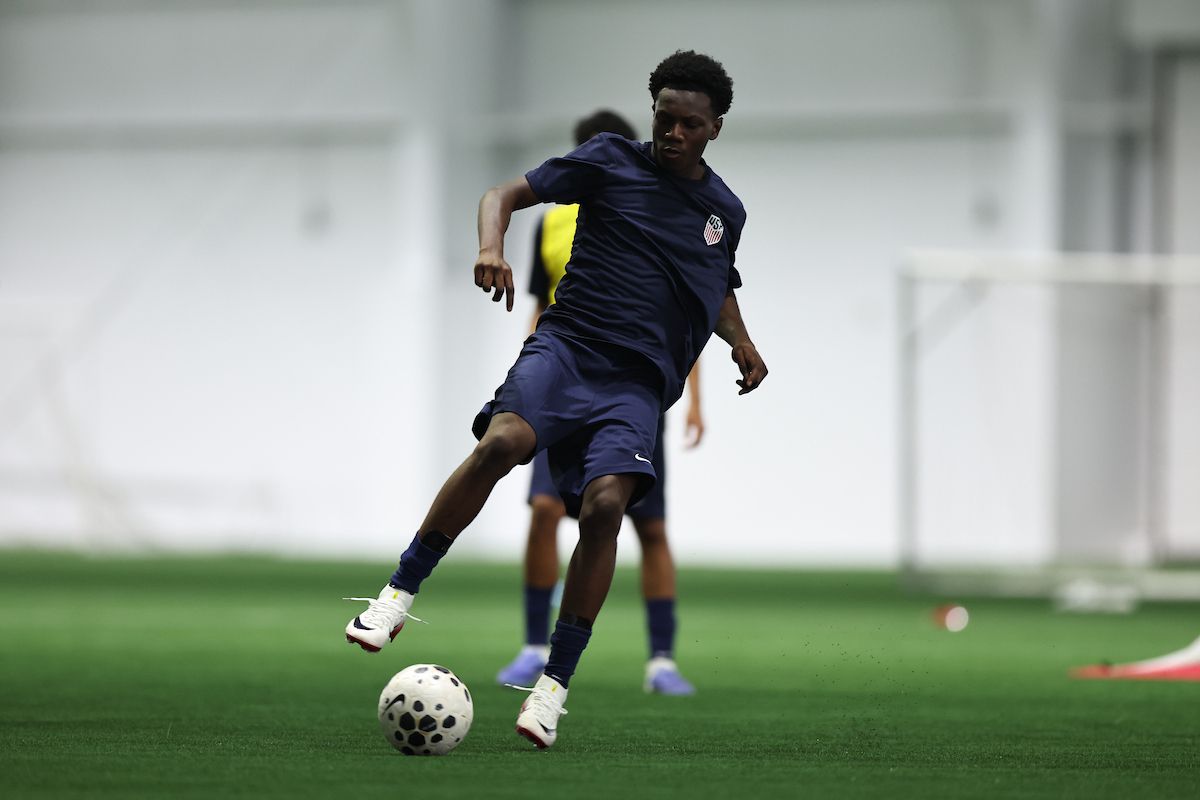 U.S. Soccer player striking a ball during an indoor training session.