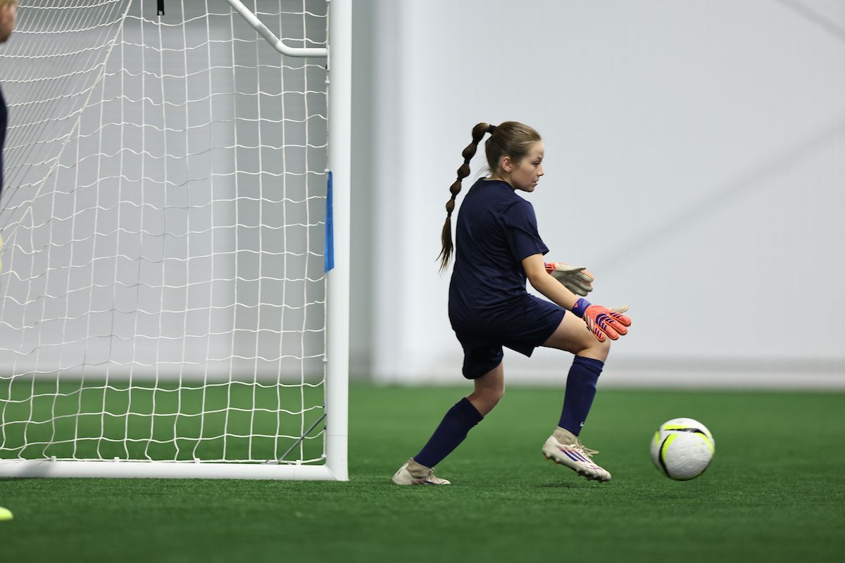 Young player pauses thoughtfully, hand on chin, during a training session.