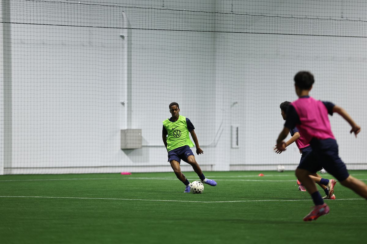 Young player dribbling a soccer ball during an indoor small-sided game.